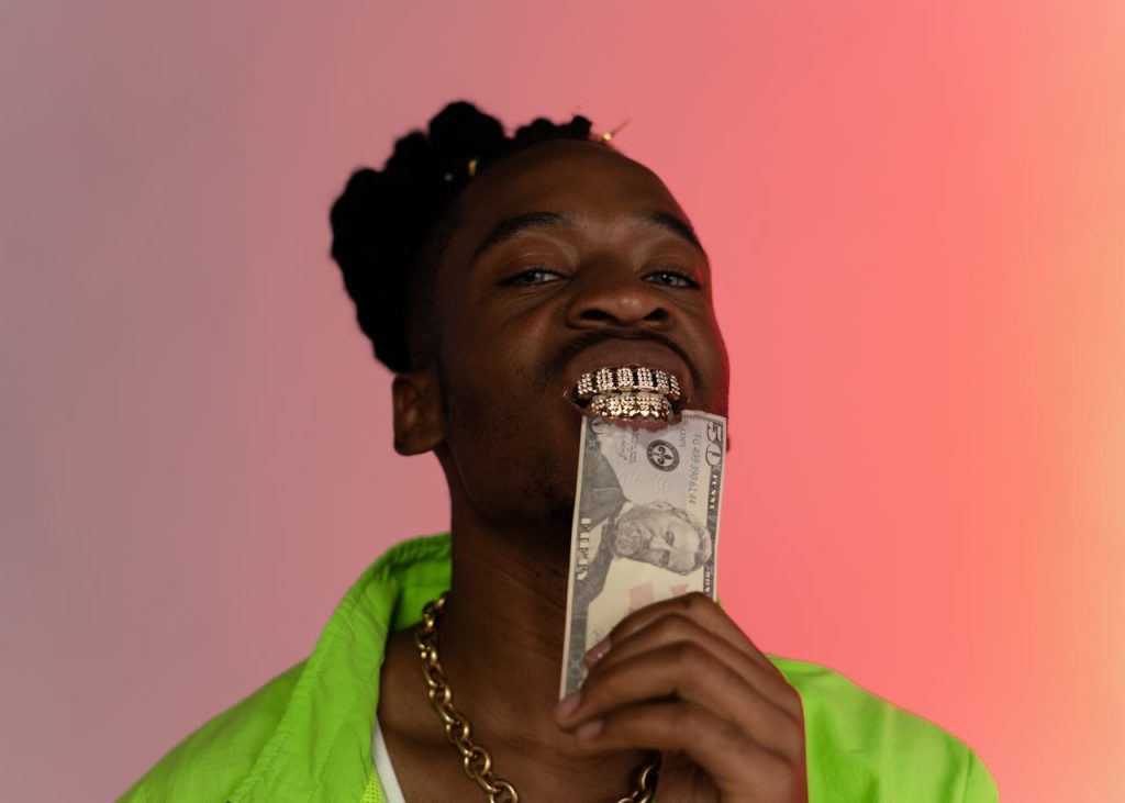 Stylish portrait of a man with grillz holding cash against a vibrant backdrop.